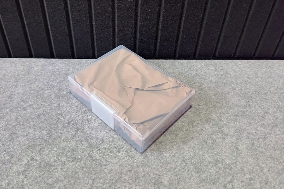 紙に包んだハードディスクをプラスチックケースに収納